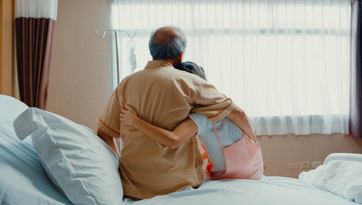 Granddaughter hugging hospitalized grandfather