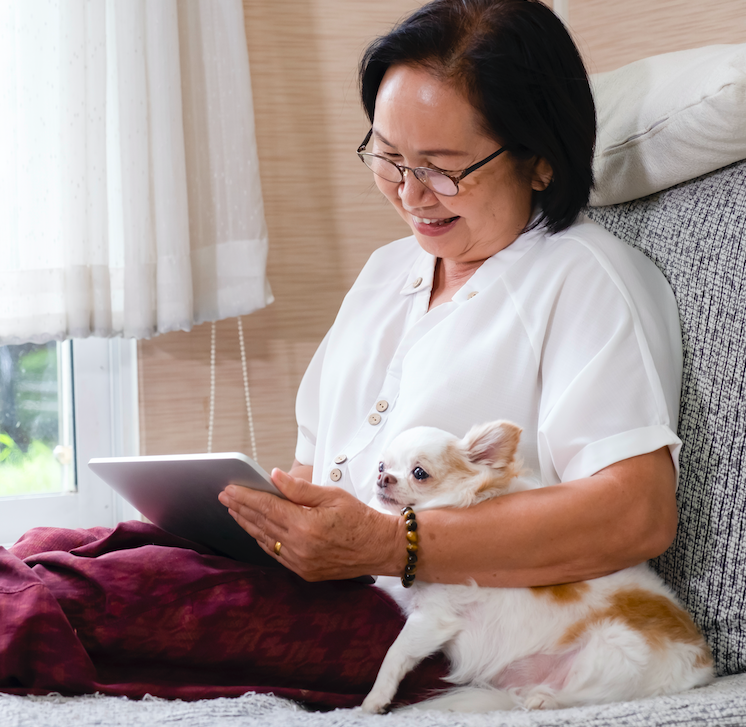 Happy woman holding dog and using electronic tablet