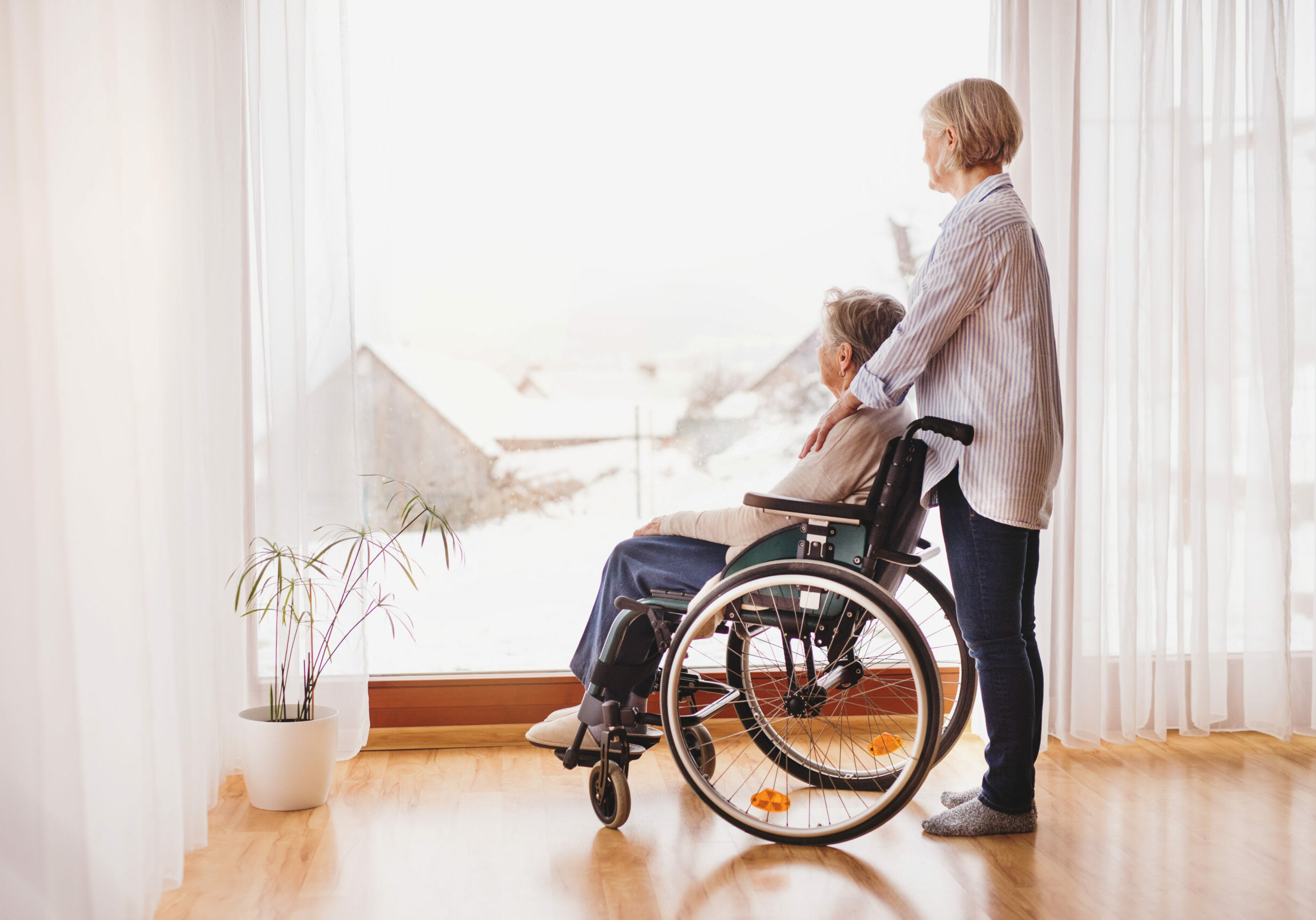 A caregiver assisting a senior woman in wheelchair.